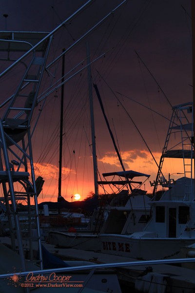 Sunset seen through the masts and gear of charter boats moored in Honokohau Harbor