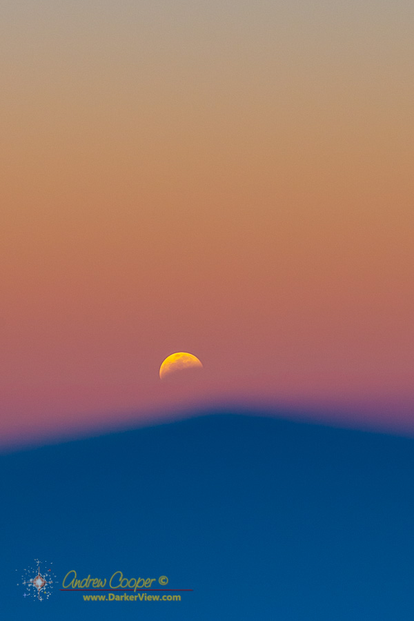 The shadow of Mauna Kea below a moon sliding into the Earth's shadow during a sunset lunar eclipse