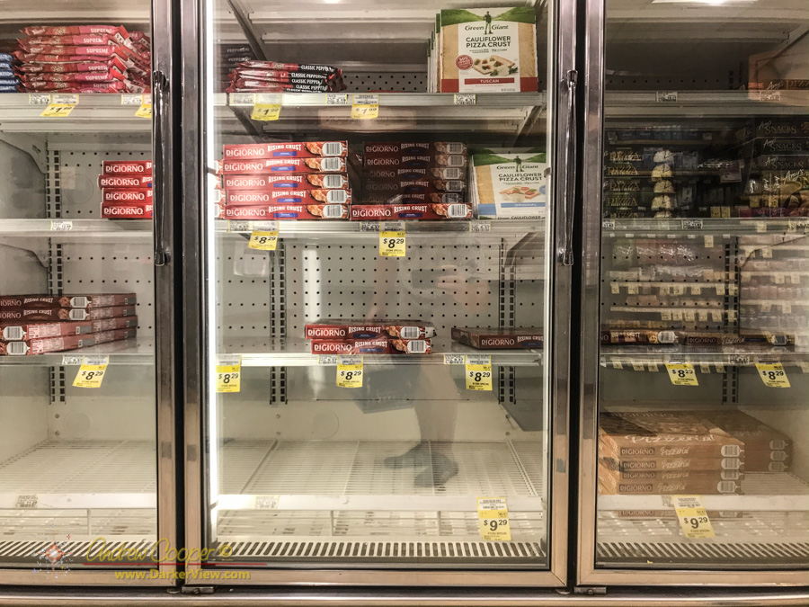 The frozen pizza case with empty shelves and a minimal selection