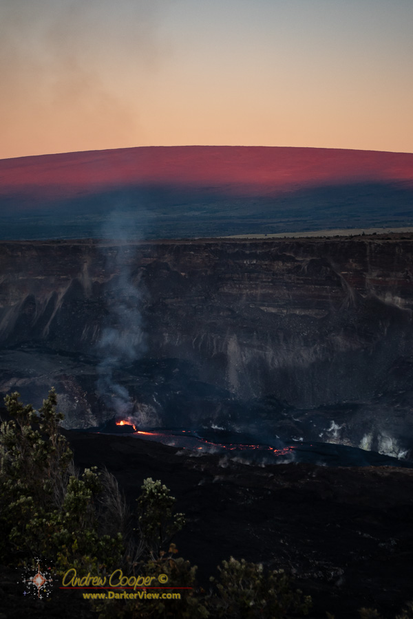 The active vent erupts lava as the dawn illuminates Mauna Loa behind