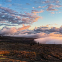 A low ground fog retreats down the mountianside at sunset from Kaʻohe